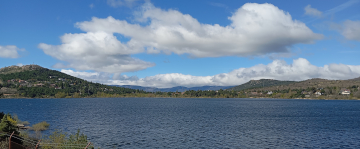 Embalse de Navacerrada con colinas verdes y cielo despejado