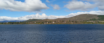 Embalse de Navacerrada con colinas y viviendas junto a la orilla
