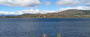 Embalse de Navacerrada con colinas verdes y casas dispersas