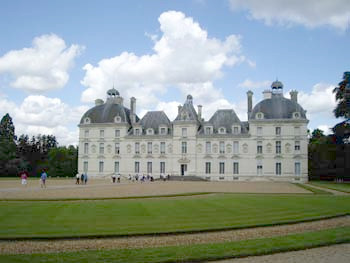 Castillo francés de estilo renacentista con jardines y visitantes en un día parcialmente soleado