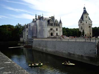 Castillo de Chenonceau sobre el río con barcas y visitantes en un día soleado